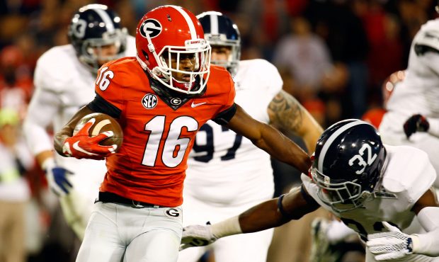ATHENS, GA - NOVEMBER 21: Isaiah McKenzie #16 of the Georgia Bulldogs stiff arms William Bussey #32...