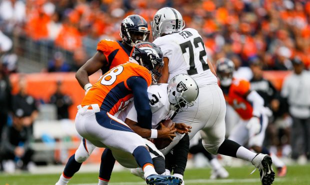 DENVER, CO - OCTOBER 1:  Quarterback EJ Manuel #3 of the Oakland Raiders is hit by outside lineback...
