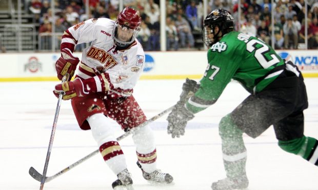 Defenseman Brett Skinner #4 of the Denver Pioneers moves the puck against defenseman Matt Smaby #27...