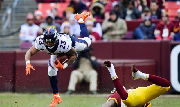 LANDOVER, MD - DECEMBER 24: Running back Devontae Booker #23 of the Denver Broncos is upended by li...