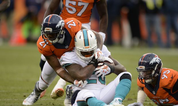 Lamar Miller (26) of the Miami Dolphins is tackled by Aqib Talib (21) of the Denver Broncos in the ...