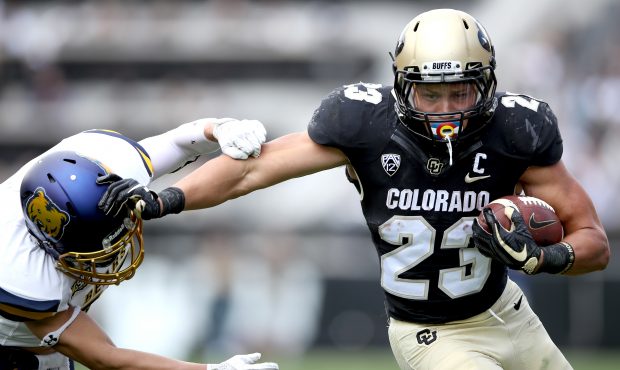 Phillip Lindsay #23 of the Colorado Buffaloes stiff arms Keifer Glau #39 the Northern Colorado Bear...