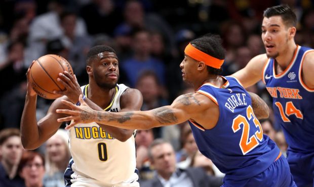 DENVER, CO - JANUARY 25:  Emmanuel Mudiay #0 of the Denver Nuggets is guarded by Trey Burke #23 and...