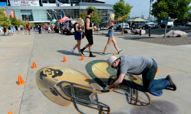 Chris Carlson works on some sidewalk chalk art prior to the Rocky Mountain Showdown between the Col...