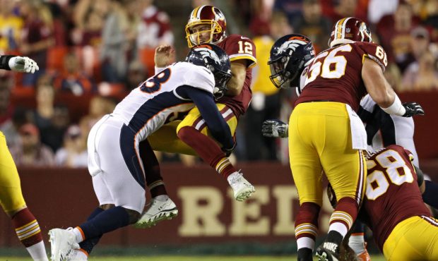 LANDOVER, MD - AUGUST 24: Quarterback Colt McCoy #12 of the Washington Redskins takes a hit after r...