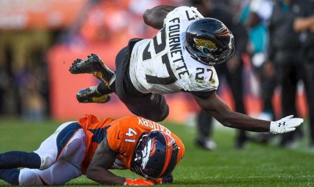 DENVER, CO - SEPTEMBER 29: Leonard Fournette #27 of the Jacksonville Jaguars is stopped by DeVante ...