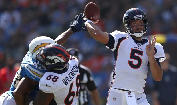 oe Flacco #5 of the Denver Broncos passes the ball under pressure from Uchenna Nwosu #42 of the Los...