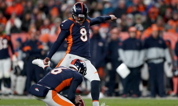 DENVER, COLORADO - DECEMBER 01: Colby Wadman #6 holds as Brandon McManus #8 of the Denver Broncos k...