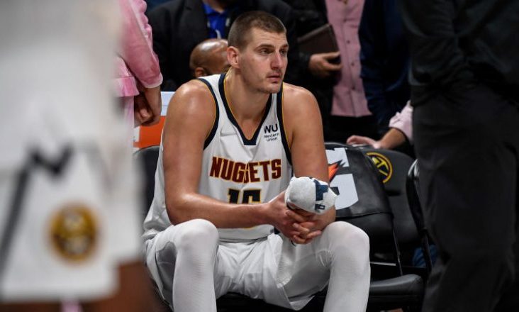 DENVER, CO - NOVEMBER 8: Nikola Jokic (15) of the Denver Nuggets sits on the bench after striking M...