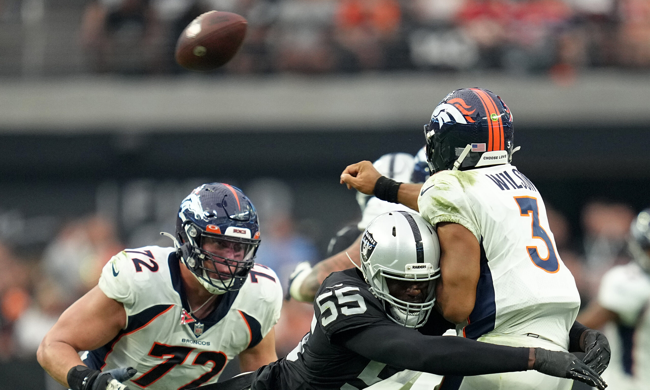 Russell Wilson #3 of the Denver Broncos throws a pass as he's hit by Chandler Jones #55 of the Las ...